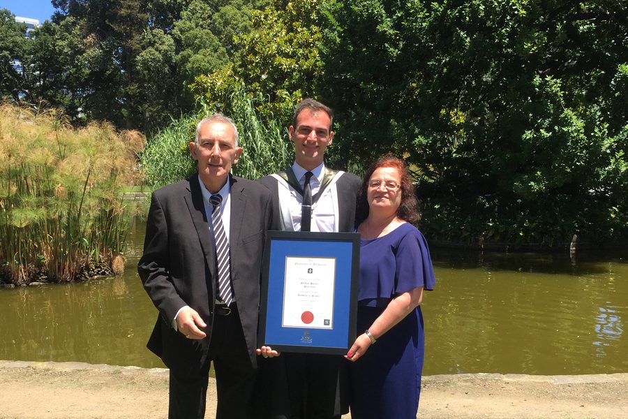 Dr Sulejman holding his testamur with his parents after his Bachelor of Science graduation