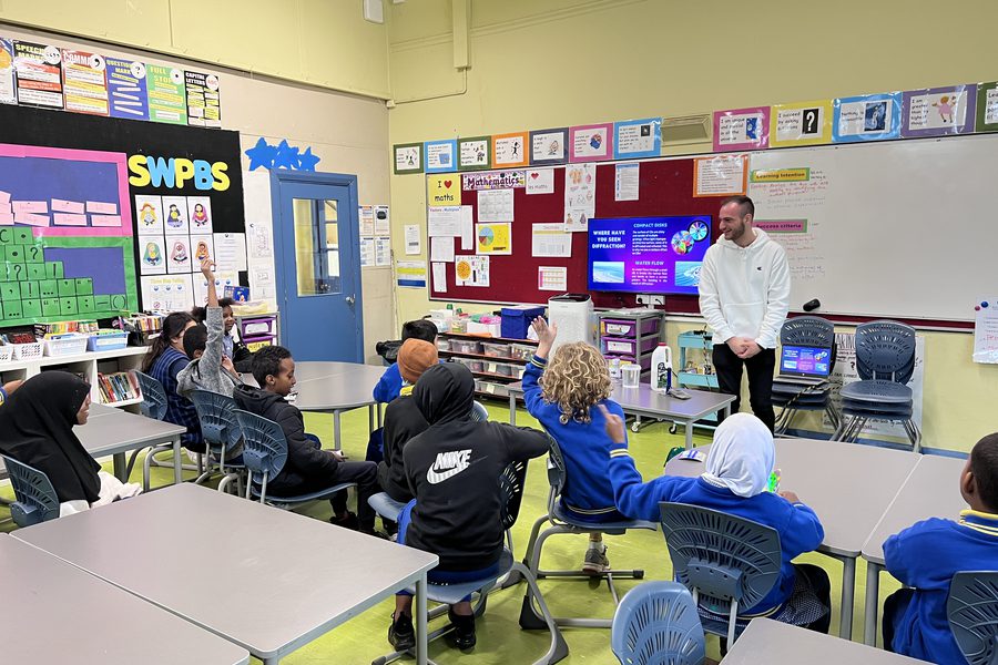 Dr Sulejman running a diffraction workshop for a primary school class, students with hands raised