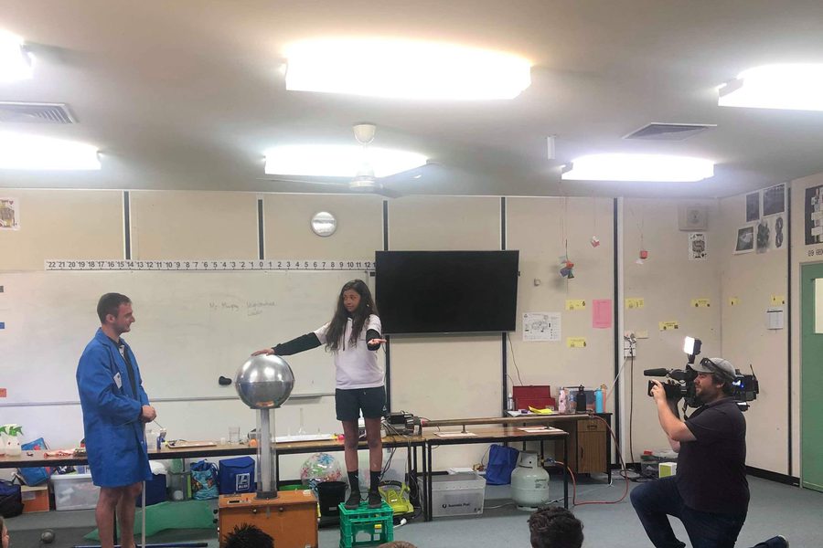 Dr Sulejman running a Van de Graaff generator demonstration for a school class while a television crew films